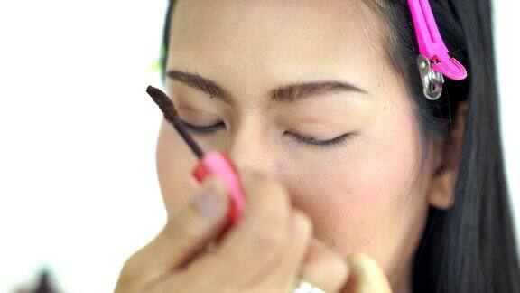 亚洲女性用特殊的眉刷在年轻女性的皮肤上涂眉粉
