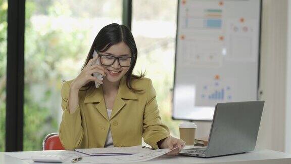 年轻的亚洲女会计在工作中处理文件忙着处理财务报告在办公室里用计算器和笔记本电脑4k30p