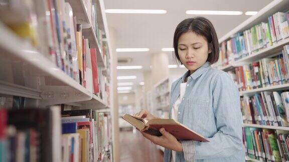 亚洲女大学生在大学校园图书馆的藏书与课本阅读