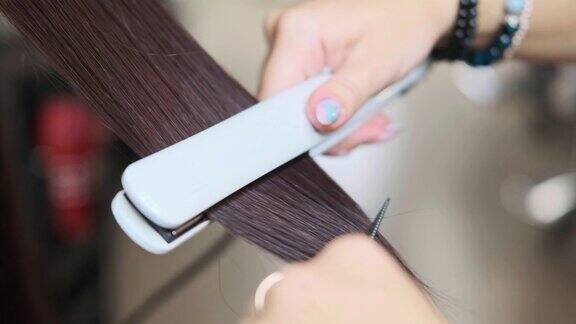 美发师在发廊里用电熨斗给顾客拉直头发