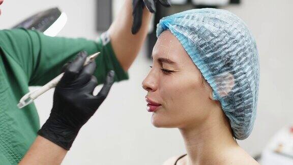 一位美容医生用笔在一位美丽的病人额头上打肉毒杆菌为一个美丽年轻的女人准备注射