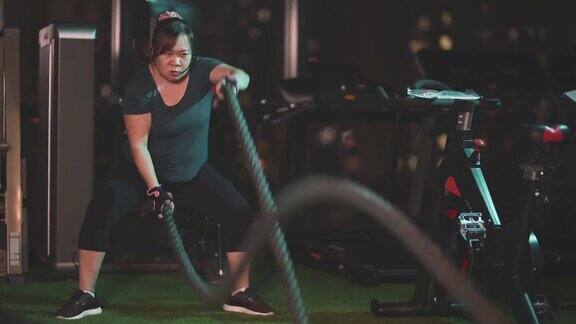 身体积极的亚洲华人中年妇女晚上在健身房练习战斗绳