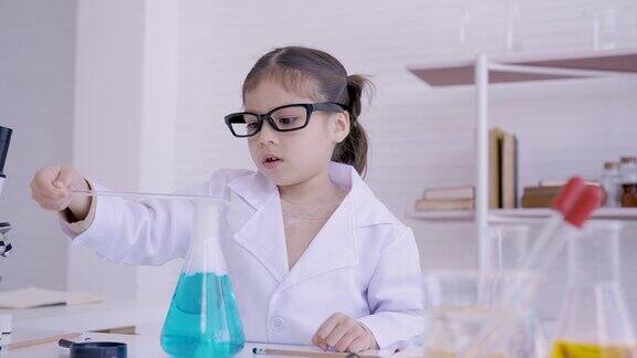 4K儿童女学生手拿烧瓶做化学实验在科学课上女孩用放大镜凝视着嘴玻璃瓶那里有轻烟冒出来
