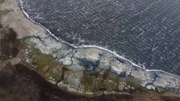 鸟瞰图在暴风雨中飞过海岸线镜头移到左边上面是布满岩石的海岸和泡沫的海浪