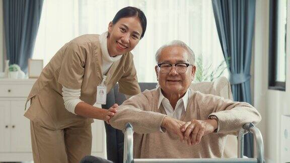 幸福生活亚洲退休高级老年男性坐在翼椅与沃克和女性护士保健给予手微笑看着相机在家里