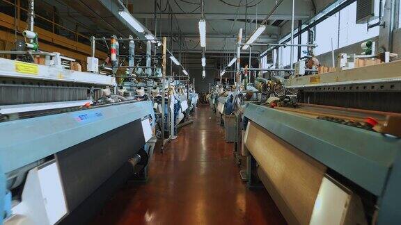 编织织机纺织工厂许多自动织布机在车间里工作编织
