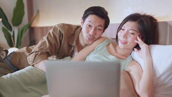 爱结婚的夫妇幸福快乐的一起在床上看流媒体电影家隔离的想法概念亚洲夫妇躺下蚌快乐的床上