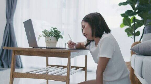 美丽的亚洲女人在家里用笔记本电脑学习