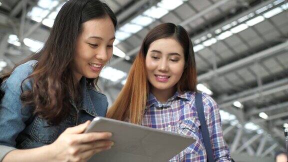 两名年轻女子在机场使用平板电脑
