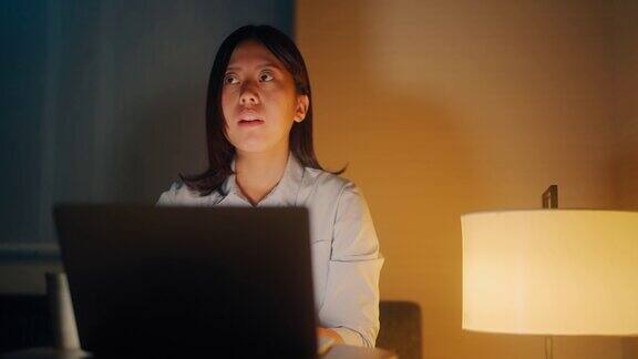 年轻的女商人在出差期间在酒店房间里用笔记本电脑工作到深夜