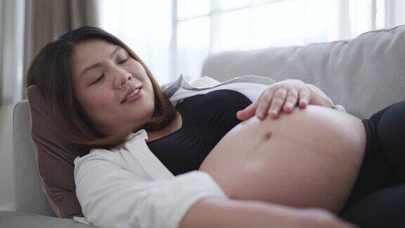 在家里的卧室里怀着肚子里的宝宝孕妇有一种爱和幸福的感觉