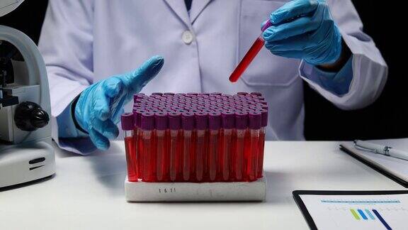 实验室助理医学科学家化学研究员拿着一根玻璃管穿过血液样本做化学实验检查病人的血液样本医学和研究概念