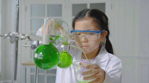 初级科学家在实验室里进行科学研究兴奋的孩子在课堂上把化学成分一个一个地混合在一起做实验女孩把化学溶液从一个试管倒到另一个试管