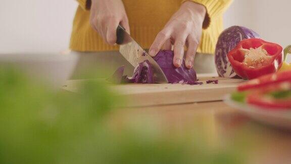 在家里的厨房里一名妇女正在砧板上切红白菜蔬菜准备做沙拉的食物