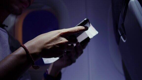 在飞机上一名男子手持登机牌、护照和智能手机