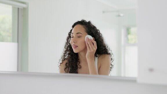 女人化妆棉和化妆棉用于家庭浴室的卸妆、清洁或面部护理女性在镜子前用化妆棉清洁面部用于皮肤病学、卫生或去角质