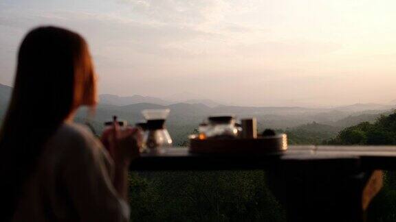 模糊的女人喝滴咖啡看着美丽的自然景色在早上