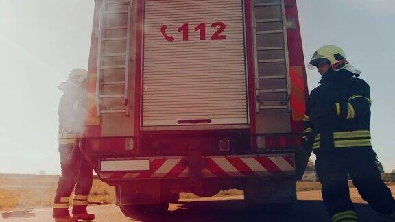 消防队员救护队乘坐消防车到达车祸现场消防队员抓住他们的设备准备消防水龙带和消防车上的装备赶往帮助受伤的人