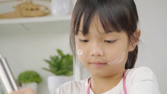 快乐的亚洲孩子在家里学习做饼干女孩在搅拌碗里搅拌面粉