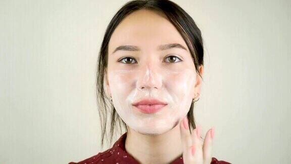 年轻漂亮的女人用洗面奶洗脸
