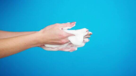 用液体肥皂或泡沫在蓝色背景上洗手预防病毒安全防护手臂使用抗菌泡沫洗手液特写