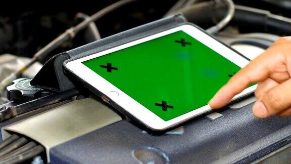 技术人员使用带绿色屏幕的平板电脑诊断汽车汽车维修概念