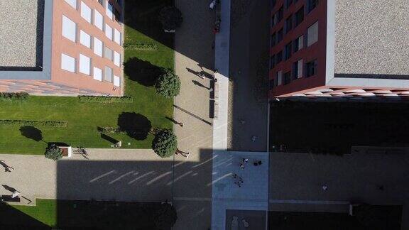 从上到下的无人机拍摄的商业或大学校园与人们从一栋楼走到另一栋楼