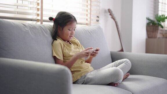 快乐女孩坐在沙发上享受在家使用手机