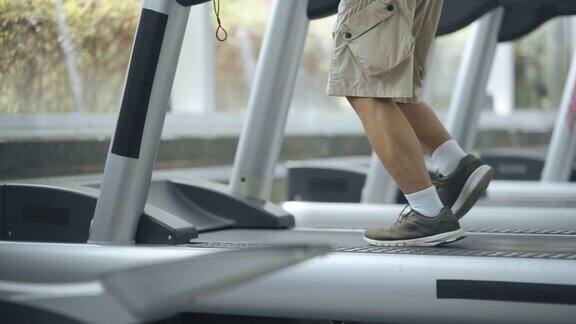 一个难以辨认的亚洲华人老人在健身房的跑步机上跑步