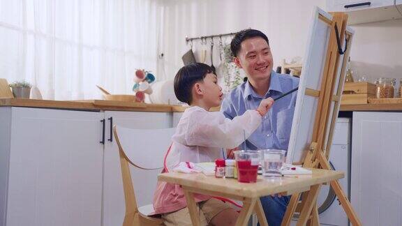 可爱的亚洲小儿子在纸上画画父母在家里快乐的家庭活动小男孩在家里的客厅和爸爸一起学习如何画艺术品享受创意