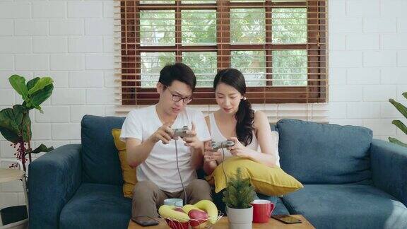 亚洲夫妇家庭在沙发上放松玩游戏