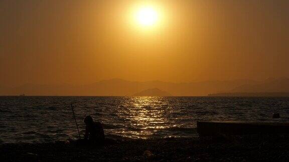 黄昏在海湾上钓鱼的女性剪影