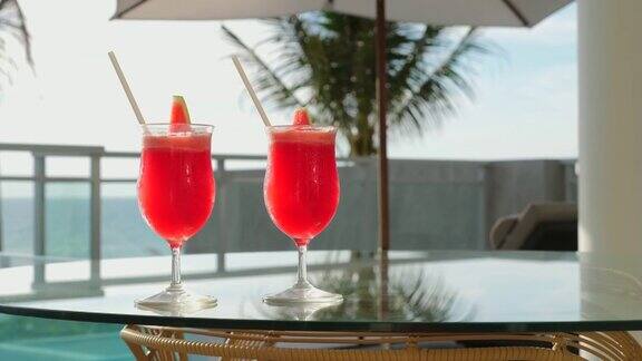 玻璃桌上的清爽饮料旁边有大海和热带棕榈树