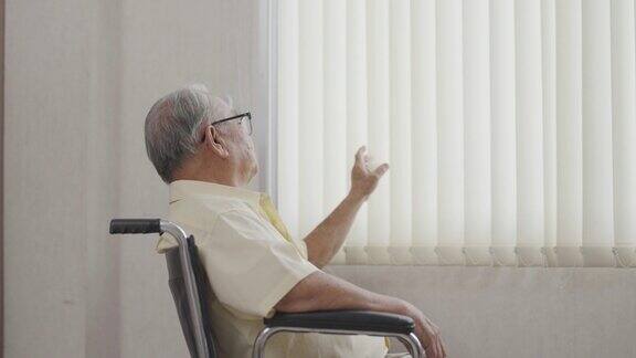 一位亚洲老人坐在轮椅上望着窗外医疗保险退休概念