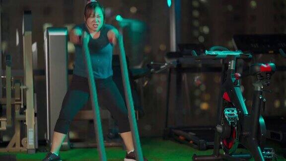 身体积极的亚洲华人中年妇女晚上在健身房练习战斗绳