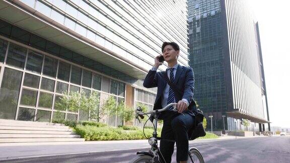 年轻的商人在自行车上使用手机
