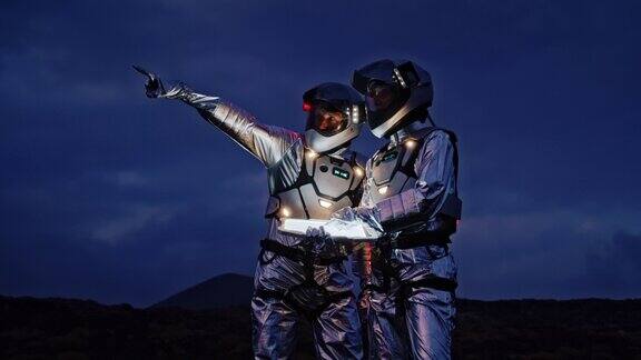 宇航员穿着未来主义服装带着发光的平板电脑在新星球上寻找路线