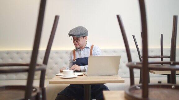 4K亚洲男人咖啡馆老板在笔记本电脑上计算财务账单