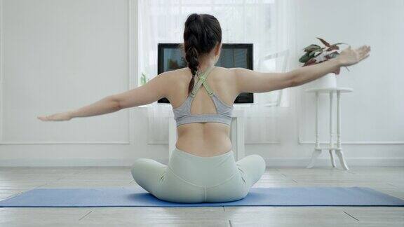 一位亚洲女性的背部通过电视在线练习瑜伽健康理念