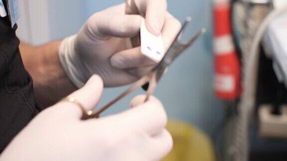 外科医生用无菌针和线打开包装在手术室里医生戴着手套拿着装有针线的无菌器械缝合伤口