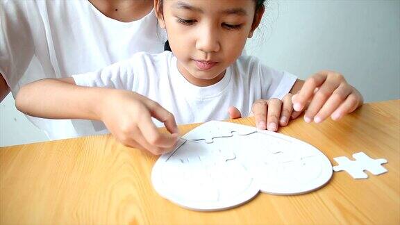 4K亚洲小女孩玩拼图游戏与妈妈选择焦点在浅景深的手
