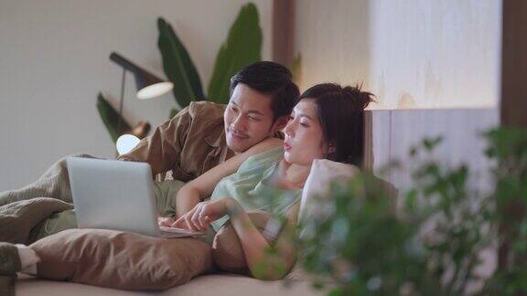 爱结婚的夫妇幸福快乐的一起在床上看流媒体电影家隔离的想法概念亚洲夫妇躺下蚌快乐的床上