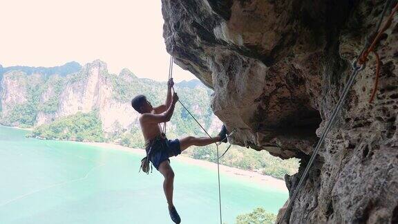 4K亚洲人在夏天爬上热带岛屿的岩石山