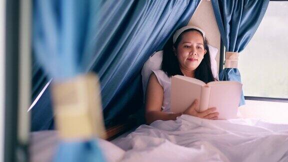 亚洲中部的女人躺在床上在一个房车看书感觉快乐和放松的假期独自旅行