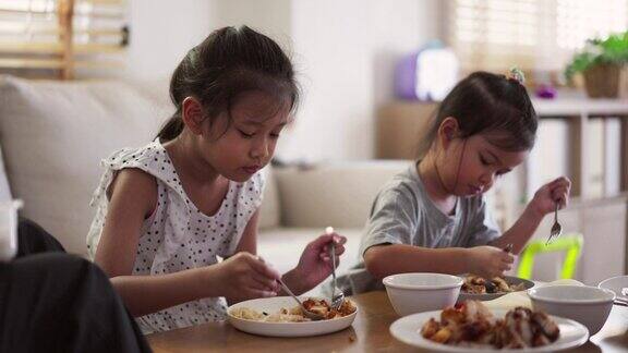 亚洲家庭兄弟姐妹在客厅的桌子上吃午饭一起看电视
