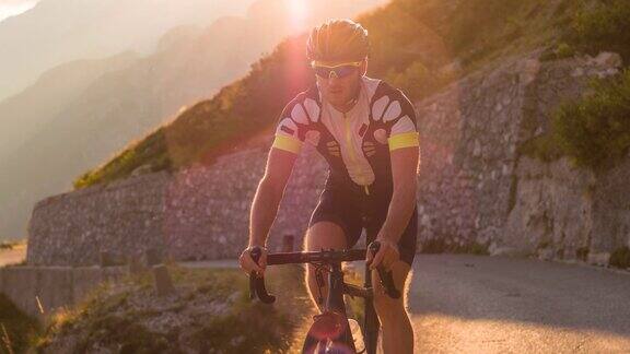 男自行车手骑着自行车在山路上被阳光照亮