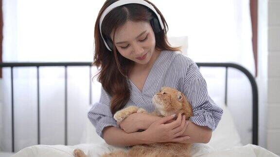 美丽的亚洲女人花她的空闲时间在家里的卧室里玩一只可爱的小猫