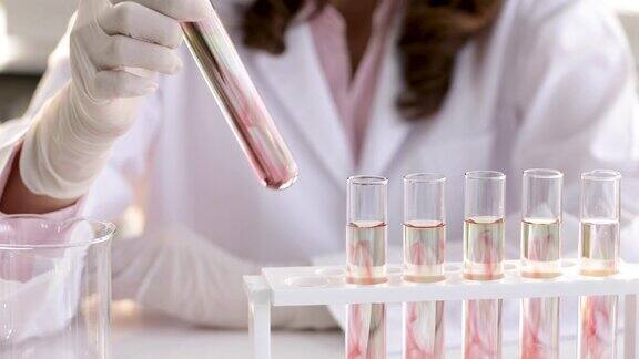 身着白大褂的女博士或研究员带着微笑在实验室里拿着玻璃试管观察混合液体的结果