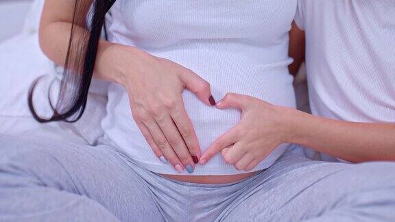 特写孕妇的肚子心脏由手指制成用于孕妇的腹部母亲的爱4kProRes