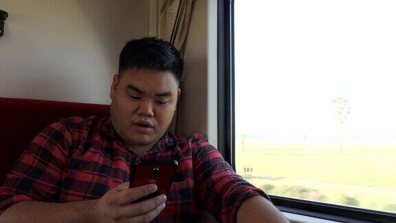 一名亚洲男子在火车上使用手机